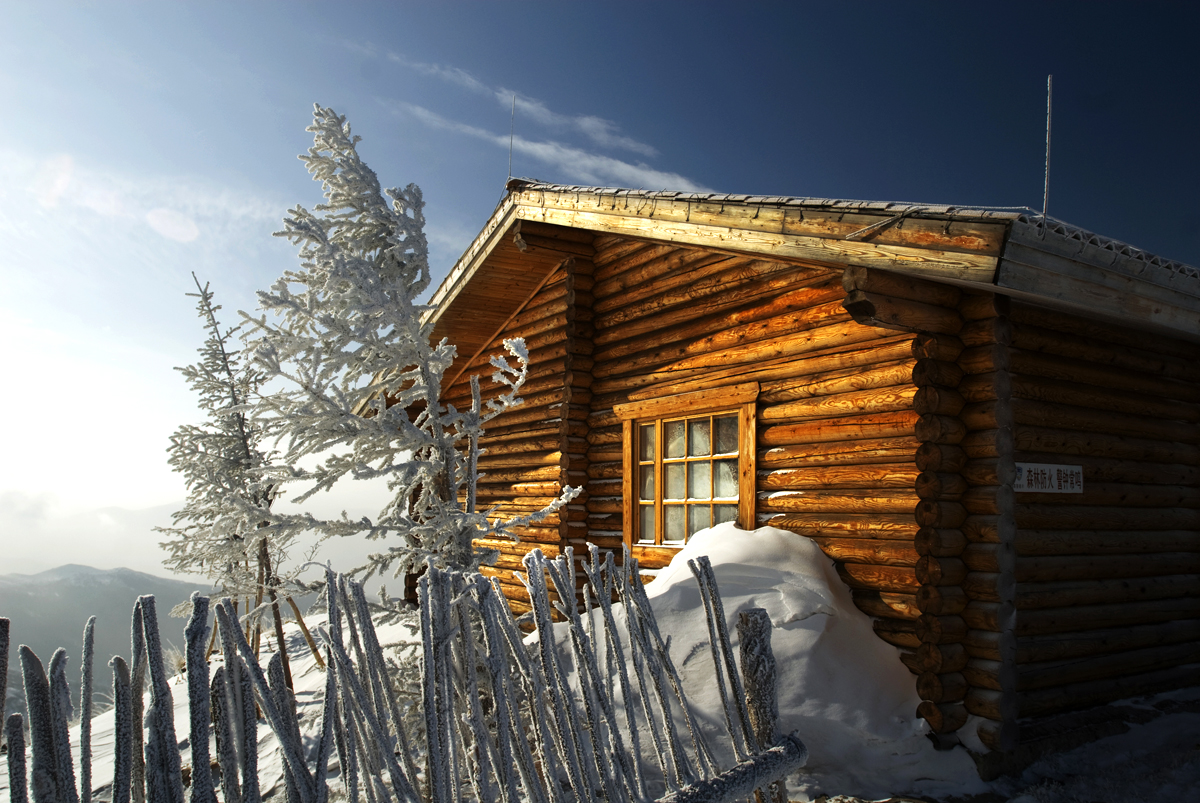 A snow-covered log cabin and frosted tree at Wanlong Ski Resort (2009)